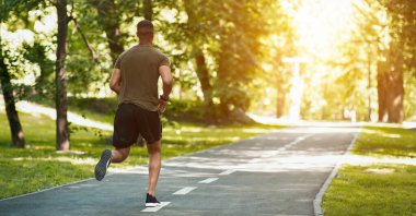Güneşli bir sabahta parkta sabah koşusu yapan bin yıllık koşucunun geriye bakışı, boş bir alan. Panorama