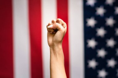Halka açık protesto gösterisi. Ciddi Afrikalı Amerikalı kadın Amerikan bayrağına karşı yumruğunu kaldırıyor.