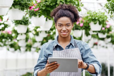 Tarım yönetiminde dijital teknoloji. Gülümseyen Afrikalı Amerikalı kız tablet kullanarak serayı kontrol ediyor.