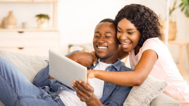 Siyah çift evde birlikte eğleniyor, dijital tablet kullanıyorlar, boş alan kullanıyorlar.