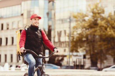 Yemek teslimatı. Şehir Bölgesi 'nde Bisiklete Binen Neşeli Kurye Yemek Teslimatı. Boş Boşluk