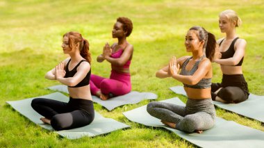 Yoga, iç huzuru için. Nilüfer çiçeğinde oturan ve yeşil parkta meditasyon yapan çeşitli genç kadınlar.