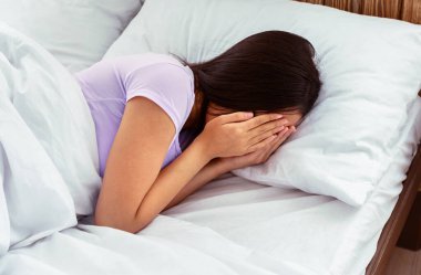 Depresyon. Tanımlanamayan Asyalı kız elleriyle yüzünü kapayarak ağlıyor. Evde yatağında ruhsal sorunları var.