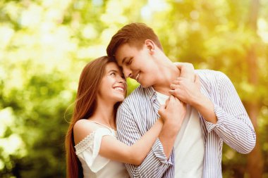 Güneşli bir yaz gününde parkta kucaklaşan sevimli bir çiftin portresi.