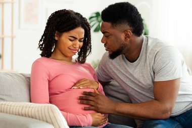 Özenli Afrikalı koca, hamile karısına evde acı içinde destek oluyor.