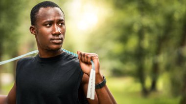 Spor aletleri ve ekipman konsepti. Parkta ip atlama eğitimi almış, fotokopi alanına bakan ciddi bir Afrikalı.