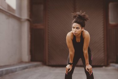 Eğitimde dinlen. Spor kıyafetli yorgun Afrikalı Amerikalı kız dışarıda koştuktan sonra soluklanıyor.
