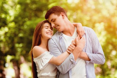 Romantik milenyum çifti parkta sarılıyor ve mutlu hissediyorlar.