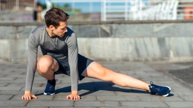 Sağlıklı yaşam tarzı, ısınma ve koşu. Spor giyim işindeki kaslı adam, sokak, panorama ve boş alanda çalışmaya başlamadan önce egzersiz yapıyor.