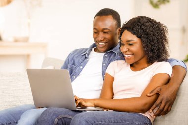 Neşeli siyah adam ve kadın dizüstü bilgisayardan, iç mekandan, kopyalama alanından fotoğraflar izliyor.