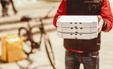 Disarida Scooter 'in yaninda duran kameraya taninamayan kurye pizza kutuları sunuyor. Restoran ve Kafe Teslimatı. Kırpılmış, Boş Boşluk