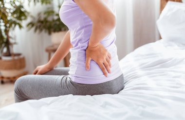 Ache 'ye dön. Tanımlanamayan, beline dokunan kadın evde yatağında oturduğu için acı çekiyor. Kırpılmış, Boşluğu Kopyala