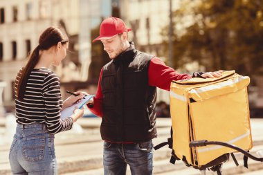 Kurye Servisi. Müşteri Kızları Restoran 'dan sipariş alıyor. Evrakları imzalıyor. Dışarıdaki teslimatçı çocukla birlikte..