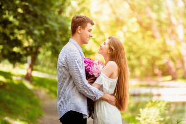 Elinde şakayık demeti olan güzel bir kız parkta sevgilisine sarılıyor.