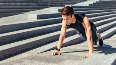 Aktif eğlence ve motivasyon. Spor giyimli, spor kıyafetli, spor ayakkabılı bir adam güneş ışığında şehir merdivenlerini çıkıyor.