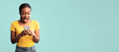 Örgülü saçlı genç bir kadın akıllı telefonunu kullanırken sevinç ifade ediyor. Sarı bir tişört ve kot şort giyiyor, görünüşe göre bir mesaj veya tebligata dalmış..