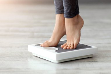 Genç bir Hintli kadın kendini evde tartıyor, fitness ve sağlıklı bir yaşam tarzına odaklanıyor. Egzersiz rutinine ve dengeli diyetine bağlıdır..