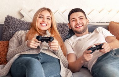 Bir çift rahat bir kanepede rahatlar, rahatlatıcı bir akşamda neşeyle video oyunları oynarlar. Oyun kontrolörlerini tutarken aynı heyecanı ve kahkahayı paylaşıyorlar.