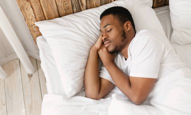 Afro-Amerikan Adam, gözleri kapalı, evinde, yatak odasında rahat bir şekilde yatarken huzur içinde uyuyor. Eğlence, Sağlıklı Erkek Uyku, Uyku Vakti Konsepti. Metin için Boşluk