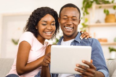 Duygusal Afrikalı çift evde dijital tablet kullanıyor, arkadaşlarıyla görüntülü görüşme yapıyor, yakın çekim yapıyorlar.