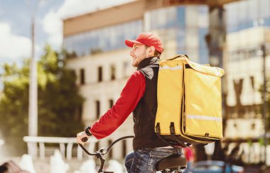 Kurye adam şehirde bisikletle yemek dağıtımı yapıyor, yemek dağıtım şirketinde çalışıyor. Metin için Boş Alan