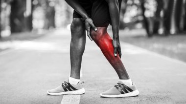 Ağrıyan bacağını ovuşturan Afrikalı bir adam parkta koşarken kramp girdi.