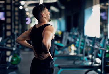 Spor salonunda belden aşağısı ağrılı genç Arap vücut geliştiricinin portresi, spor yaralanmasından sonra acı çeken Orta Doğu 'lu erkek sporcunun acı dolu bölgelerine sürtünmesi, bel omurgasının incinmesi, Kopya Boşluğu