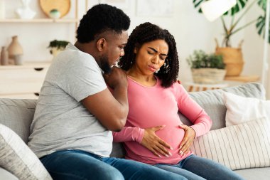 Özenli Afrikalı Amerikalı koca hamile karısına acı içinde destek oluyor. İç mekan, fotokopi odası.