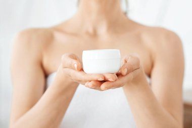 Genç kadın ellerinde vücut kremi ya da yüz kremi olan kavanoza yakın çekim, vücut bakımı konsepti