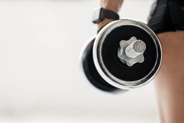 Kas ve kalp atış hızı takibi egzersizleri. Spor giyim ve spor giyim sektöründe orta yaşlı bayan sporcu. Spor salonunun ya da evin içinde dambılı tutun. Kapatın, boş alan, kırpılmış, stüdyo çekimi.