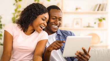 Evinde dijital tablet kullanan neşeli siyah erkek ve kadın, boşluğu kopyala