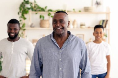 Üç adam gülümsüyor ve bitki dolu parlak bir odada birlikte duruyorlar. Ortam sıcak ve davetkar. Arkadaş ve aile toplantısı için mükemmel..