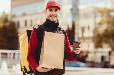 Neşeli Kurye Kahve ve Kağıt Paket Taşıyarak Şehir Bölgesi 'nde Yemek Getiren Adam. Yemek Teslimatı Konsepti