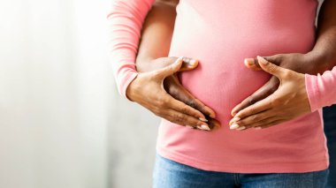 Afrikalı hamile çiftin yakın çekimleri. Birbirlerinin üzerine ellerini koyuyorlar. Karı göbeğine, fotokopi alanı olan panoramaya.