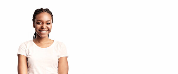 A young woman wearing a white t-shirt stands confidently with a bright smile. Her braided hair and approachable demeanor exude warmth and positivity, creating an inviting presence.