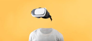 Bir kullanıcı, parlak sarı bir arkaplana karşı görünür bir kafası veya yüzü olmayan sanal bir gerçeklik kulaklığı kullanır. Bu kurulum, deneyimler için son teknolojiyi ön plana çıkarıyor.