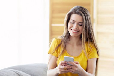 Güzel bayan evde internet iletişimi, iş ya da eğlence için cep telefonu kullanıyor.