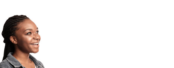 A young woman with braids smiles brightly while facing slightly to the right. Her expression reflects happiness and positivity, creating an inviting atmosphere.