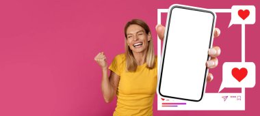 Gülümseyen bir etkili, parlak pembe bir arka plana karşı duruyor. Elinde akıllı bir telefon var ve ekranı gösteriyor. Çevrimiçi etkileşimlerinden, sosyal medyaya olan coşkusundan dolayı heyecanlı görünüyor..