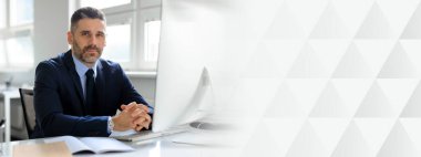 Orta yaşlı bir işadamı iyi aydınlatılmış bir ofiste masasında dikkatle oturur. Takım elbise giymiş ve özenle çalışıyor gibi görünüyor. Başarılı bir yaşam tarzı, kopyalama alanı.