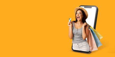 Mutlu bir alıcı, elinde alışveriş poşetleri ve ödeme kartı olan bir web mağazası gösteren akıllı bir telefonla iletişim kurar. Bu resimde modern ticaret ve dijital alışveriş kolaylığı sergileniyor.