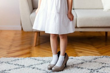 Sevimli Asyalı kız, yüksek topuklu ayakkabı giyen, kameraya gülümseyen. Childs Giyim ve Tarz Konsepti