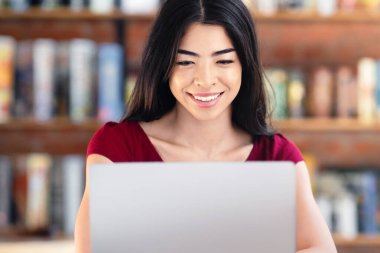 Çevrimiçi Kavram Çalışıyor. Gülümseyen Asyalı Kız Kafe 'de dizüstü bilgisayar kullanıyor, Cihaz ekranına bakıyor,