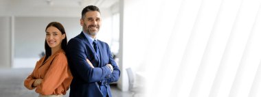 İki profesyonel, takım çalışması ve işbirliği sergilemek için parlak bir ofiste sırt sırta dururlar. Kurumsal dünyada başarı ve adanmışlığı temsil ediyorlar, kopyalama alanı.