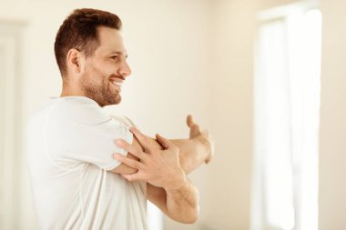 Neşeli adam evde ayakta duran esneyen kollar egzersizi yapıyor. Sabah Beden Eğitimi, Erkek Spor, Günlük Spor Rutin Konsepti. Metin için Boşluğu Kopyala
