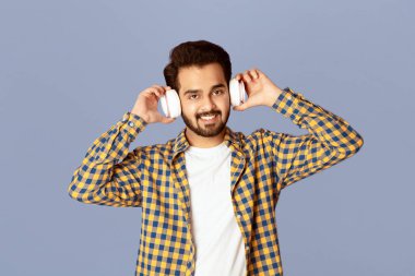 Gülümseyen Hintli adam kulaklıkla en sevdiği müziği dinliyor.