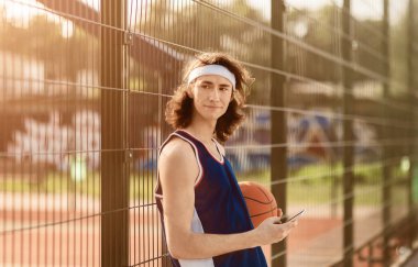 Yakışıklı beyaz sporcu dışarıda cep telefonuyla internete göz atıyor.