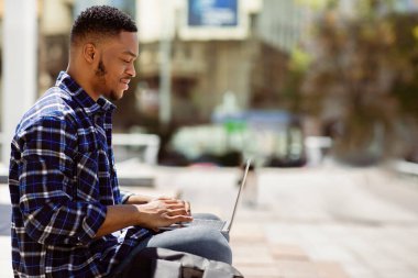 Yaşam tarzı kavramı. Sıradan bir Afrikalı 'nın portresi dışarıda oturmuş, bilgisayar ve daktilo ile, kopyalama alanı, seçici odak