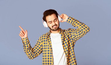 Kulaklıklı havalı Hintli adam en sevdiği müziğin tadını çıkarıyor. Leylak arka planda, panorama