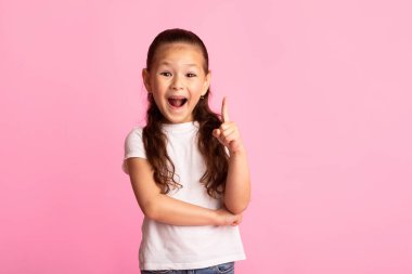 Evreka. Heyecanlı Asyalı çocuğun mükemmel bir fikri var. Parmakla işaret ediyor. Pastel pembe stüdyo duvarında izole edilmiş.